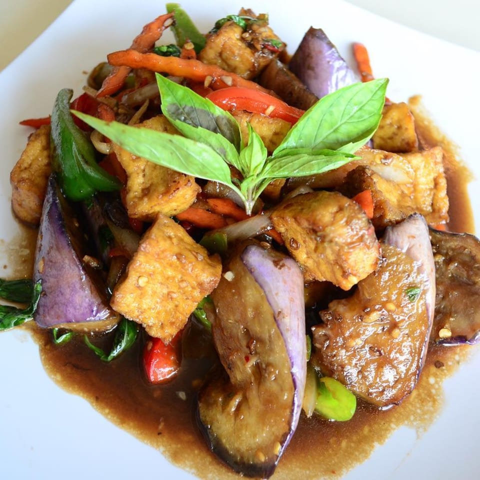 Pattaya Bay Thai Restaurant's stir-fried tofu, eggplant, and vegetables in a rich sauce, garnished with basil.