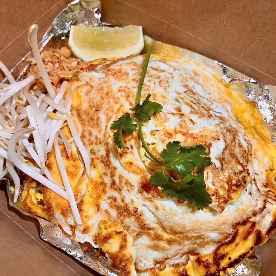 Pattaya Bay Thai Restaurant's Pad Thai with egg, bean sprouts, lime, and cilantro in a takeout container.