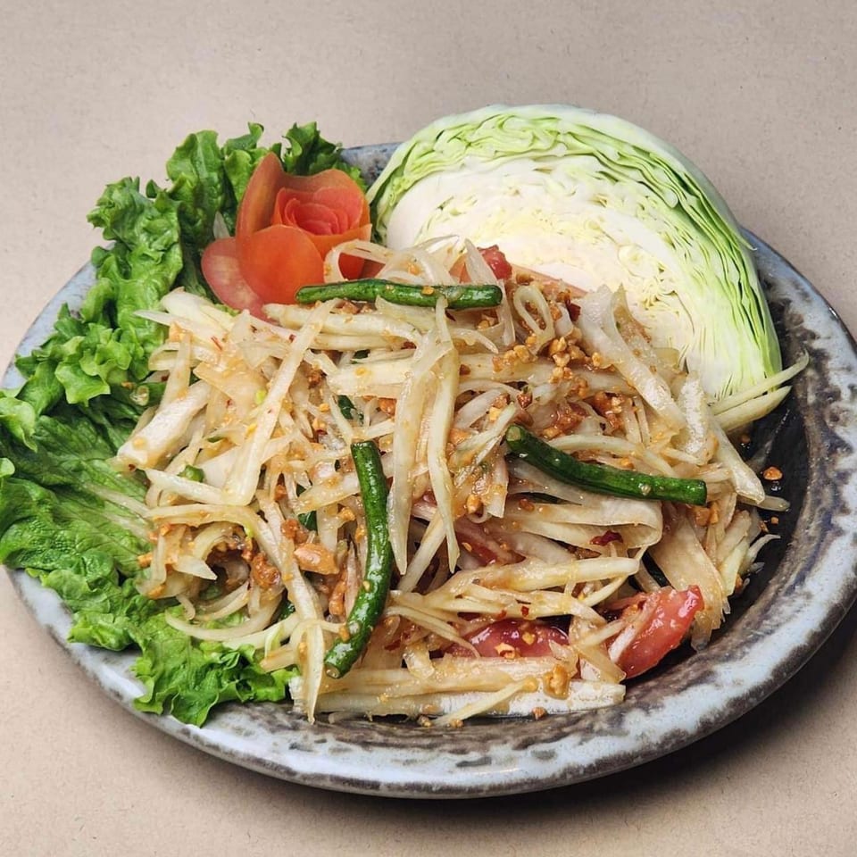 Som Tum, a Thai papaya salad, with green beans, tomatoes, peanuts, lettuce, and cabbage.