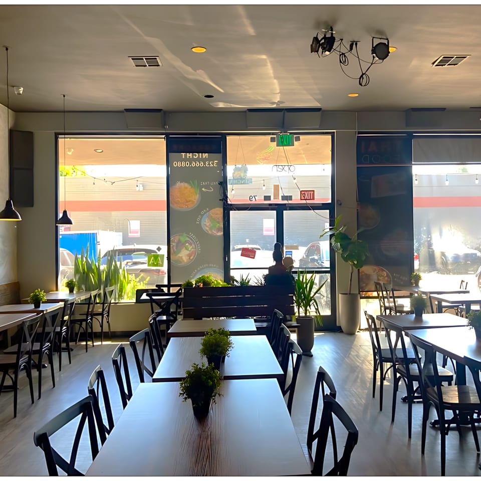 Interior of Pattaya Bay Thai Restaurant with empty tables, chairs, and large front windows.